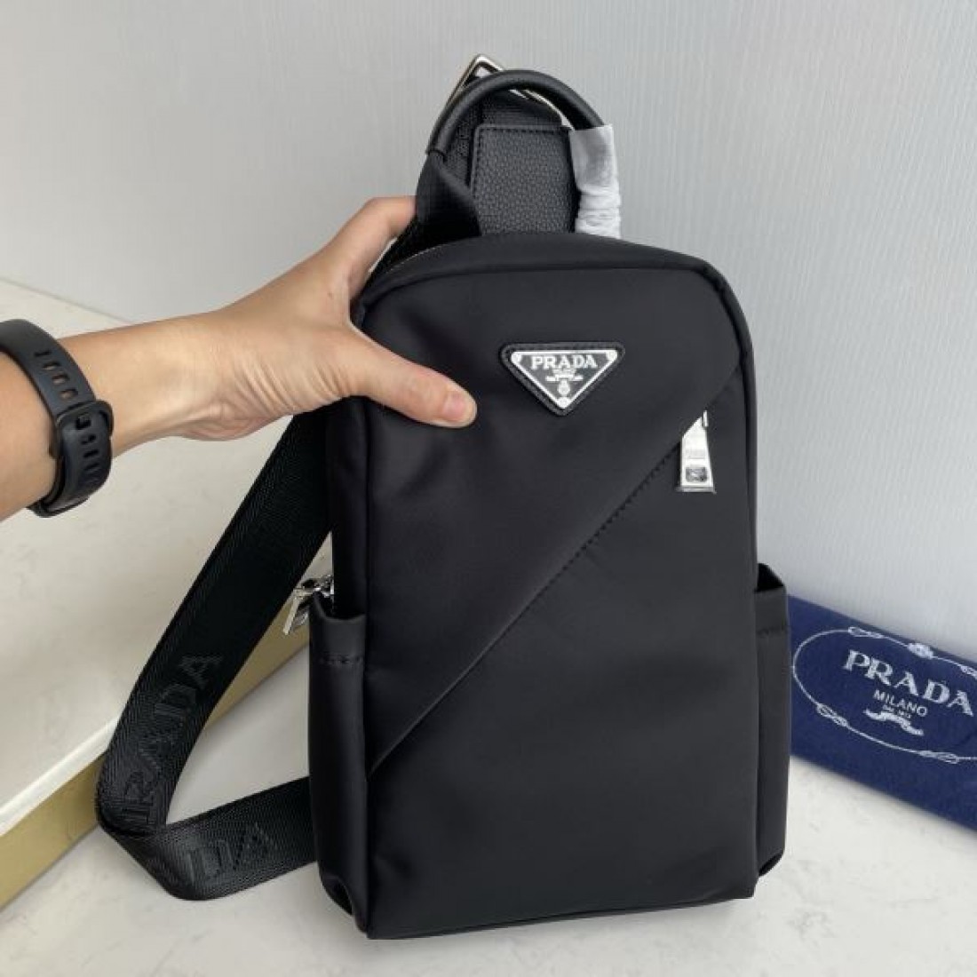 シンプル 高級感 PRADA プラダ コピー ボディバッグ ナイロン素材 縦型スリングバッグ ミニマルデザイン フロントロゴ 三角プレート 軽量設計 快適フィット