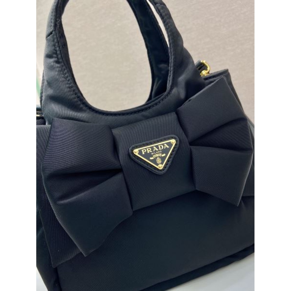 シンプル 洗練 PRADA プラダ コピー バッグ コンパクトハンドバッグ ナイロンボディ リボンディテール ロゴプレート 取り外し可能ストラップ 日常万能